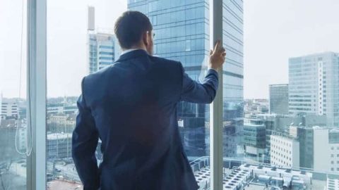A businessman looks out his office over the city.