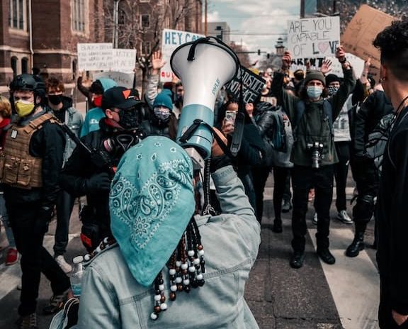 A gathering of protestors and marchers led by a woman with a megaphone.